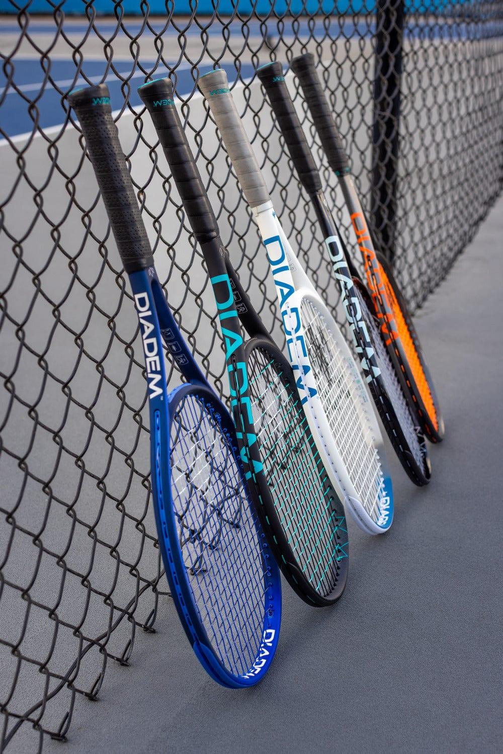 A line-up of Diadem tennis rackets leaning against a court fence